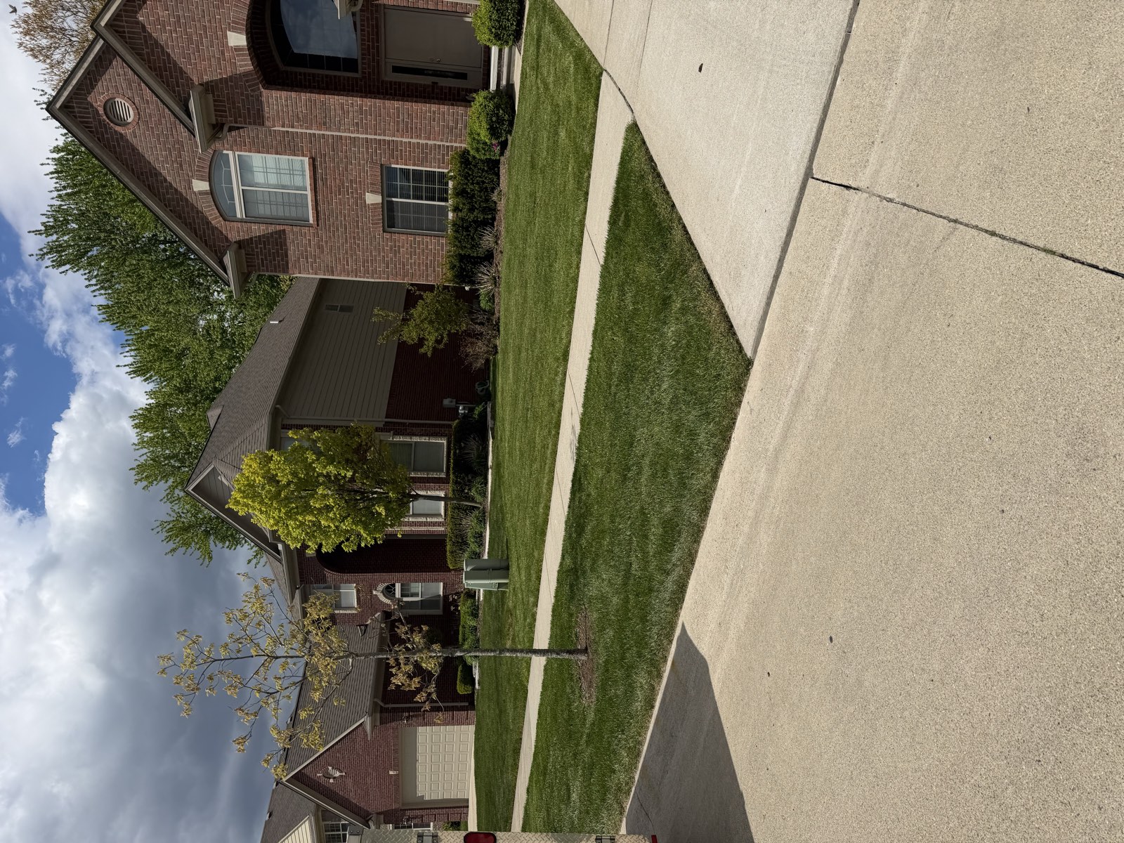 A lush, freshly striped front lawn in front of a brick home, representative of the Macomb County properties Summit services