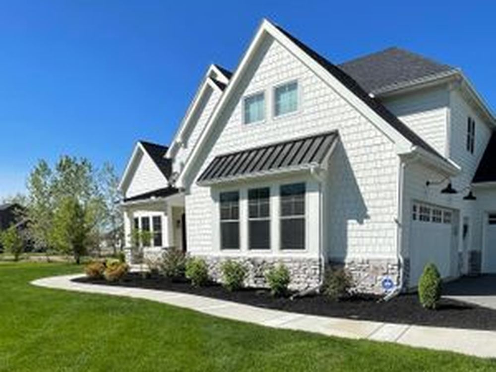 A freshly mulched landscape bed along an upscale shingle-style home