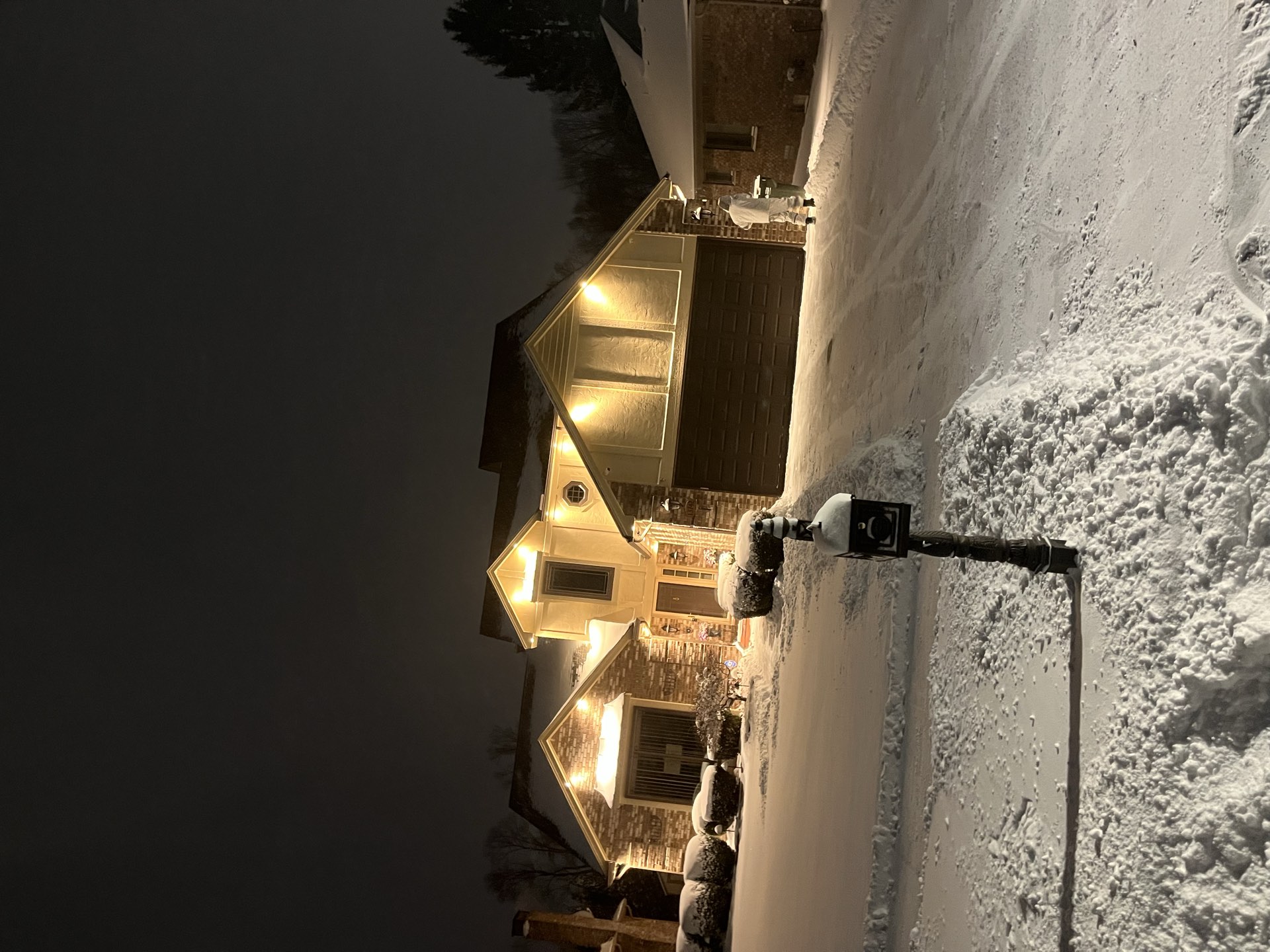 A snow-covered driveway and home at night before a storm in Macomb County