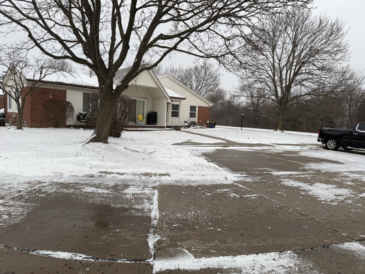A plowed residential driveway and parking area with snow cleared to the edges
